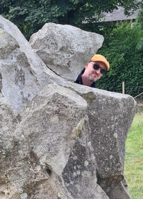 Red Handpan looking out over grassy fields, city in the distance in a hazy pink and blue gradient sky